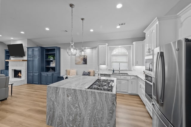 kitchen with pendant lighting, appliances with stainless steel finishes, white cabinetry, and a center island