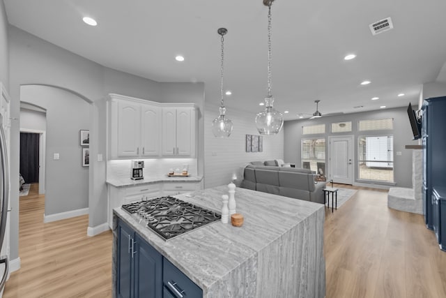 kitchen with a center island, blue cabinetry, visible vents, open floor plan, and white cabinets