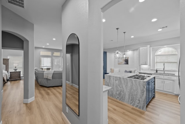 kitchen featuring arched walkways, white cabinets, a sink, and visible vents