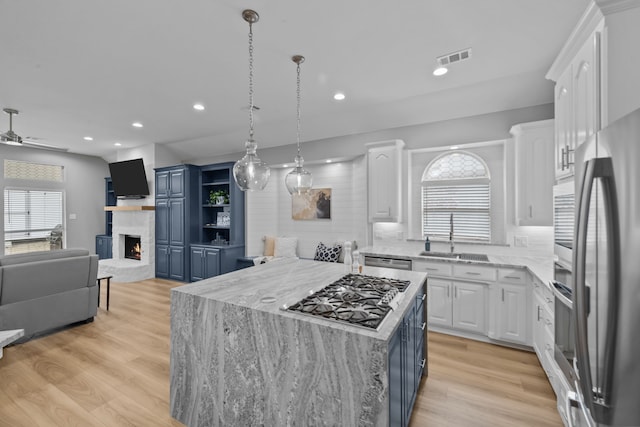 kitchen with a center island, blue cabinetry, open floor plan, white cabinets, and a sink