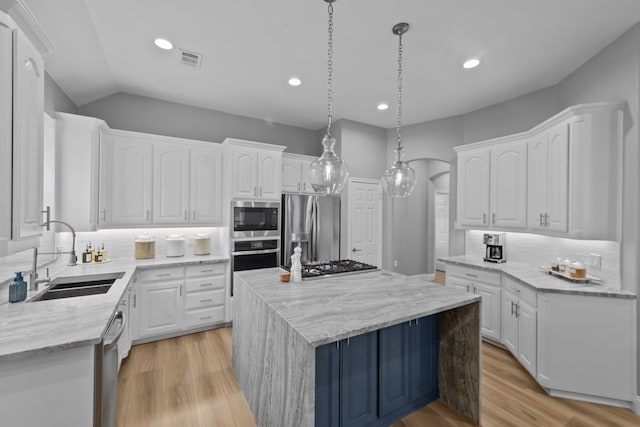 kitchen featuring appliances with stainless steel finishes, white cabinets, a sink, and decorative light fixtures