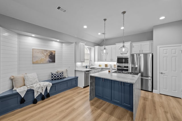 kitchen with a kitchen island, appliances with stainless steel finishes, white cabinetry, pendant lighting, and a sink