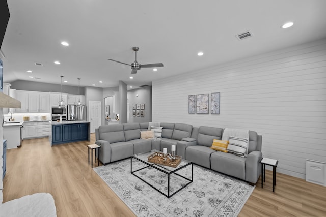 living room with arched walkways, recessed lighting, visible vents, a ceiling fan, and light wood-type flooring