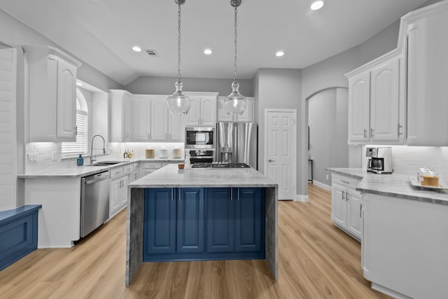 kitchen featuring white cabinets, appliances with stainless steel finishes, a center island, pendant lighting, and a sink