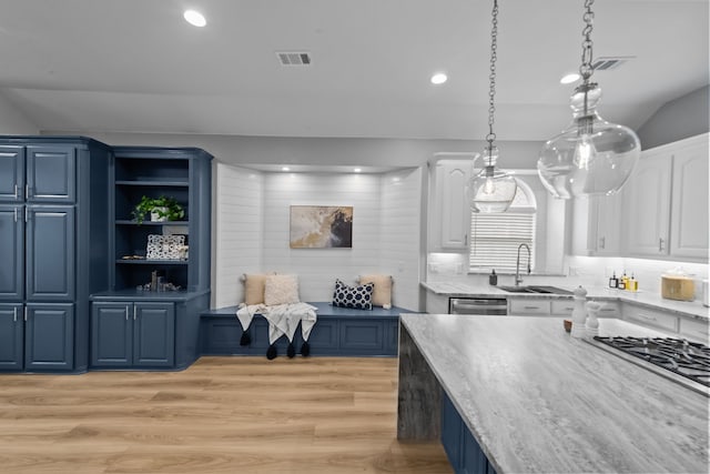 kitchen with visible vents, white cabinets, decorative light fixtures, blue cabinetry, and a sink