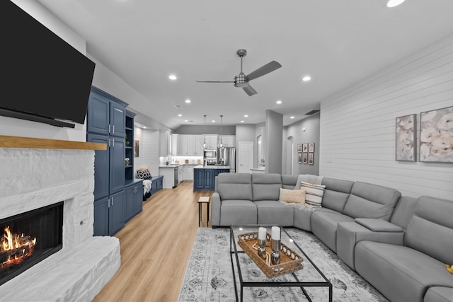 living room with recessed lighting, light wood-style flooring, ceiling fan, and a stone fireplace