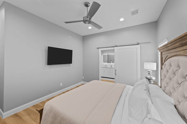 bedroom featuring recessed lighting, visible vents, a barn door, light wood-type flooring, and baseboards