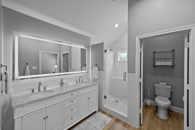 full bathroom with lofted ceiling, a shower stall, a sink, and wood finished floors