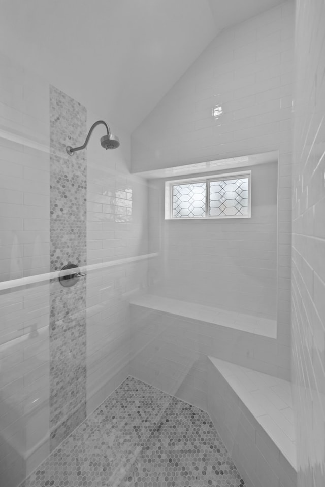 full bathroom with vaulted ceiling and tiled shower