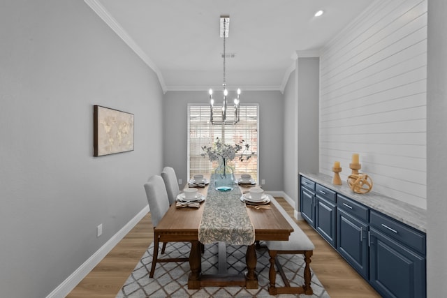 dining space with a chandelier, light wood finished floors, baseboards, and crown molding