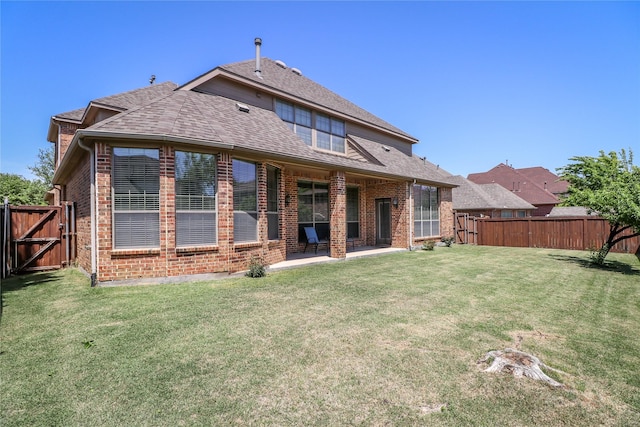 rear view of house featuring a yard, a fenced backyard, and brick siding