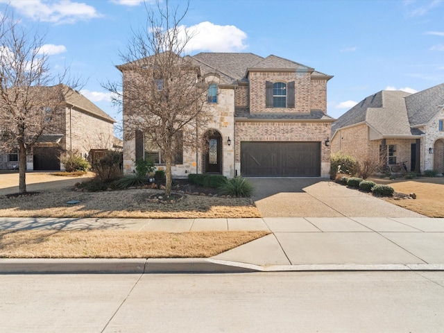 french provincial home featuring a garage, driveway, brick siding, and stone siding