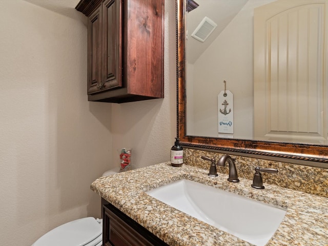 bathroom featuring toilet, a textured wall, vanity, and visible vents