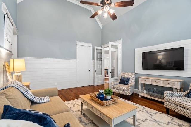 living area featuring a wainscoted wall, a ceiling fan, dark wood-style floors, and high vaulted ceiling