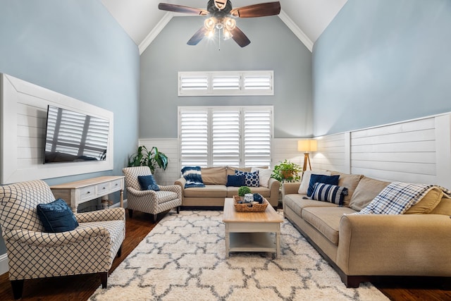 living room featuring a ceiling fan, high vaulted ceiling, dark wood-type flooring, and wainscoting