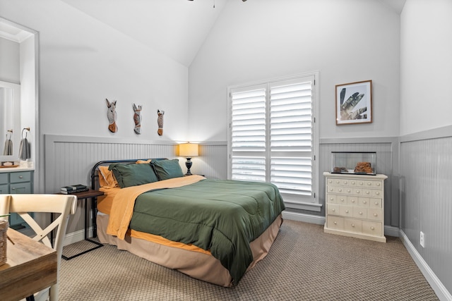 carpeted bedroom featuring vaulted ceiling and wainscoting