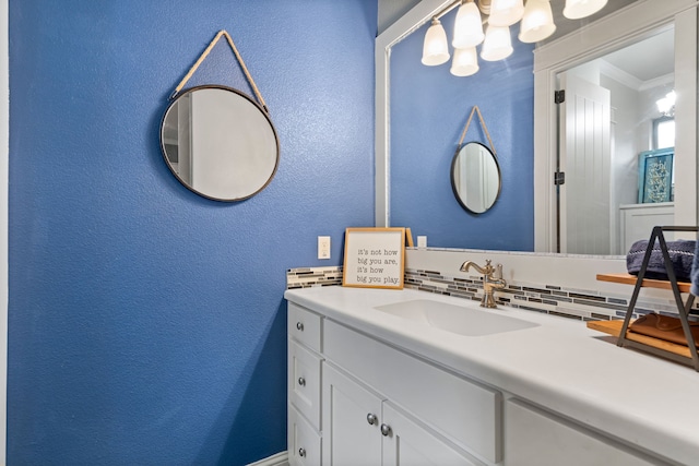 bathroom with a textured wall, tasteful backsplash, vanity, and crown molding