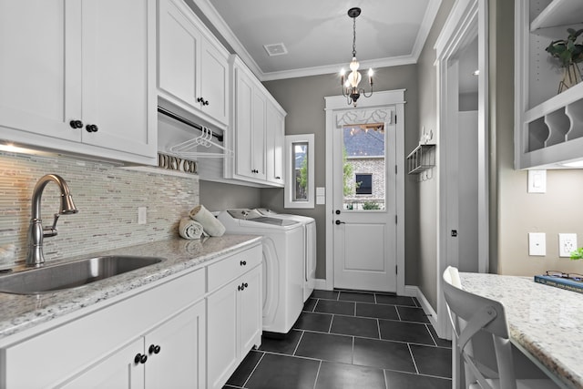 washroom featuring cabinet space, dark tile patterned flooring, independent washer and dryer, crown molding, and a sink