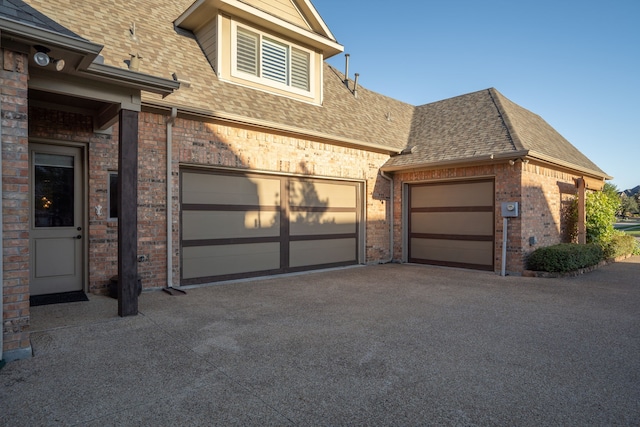 view of front of property with a shingled roof, brick siding, driveway, and a garage