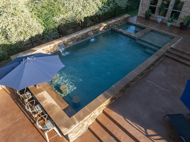 view of swimming pool featuring a pool with connected hot tub, fence, outdoor dry bar, and a patio