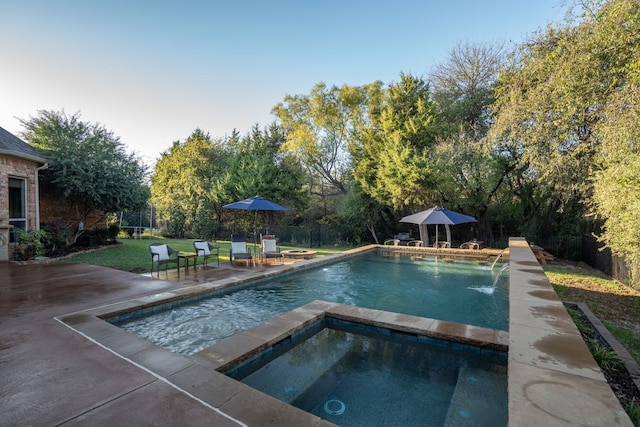 pool featuring a patio area, a fenced backyard, and an in ground hot tub