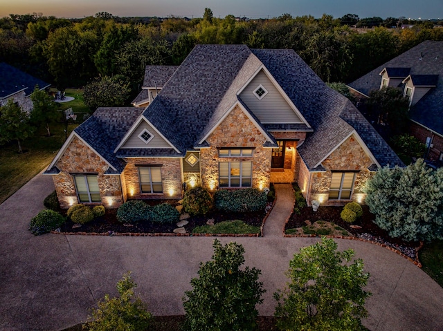 view of front of property with driveway and stone siding