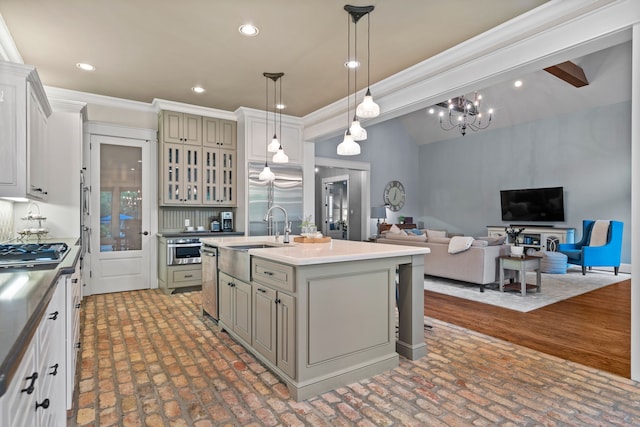 kitchen featuring an island with sink, open floor plan, decorative light fixtures, stainless steel appliances, and a sink