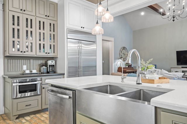 kitchen with stainless steel appliances, light countertops, hanging light fixtures, glass insert cabinets, and a sink