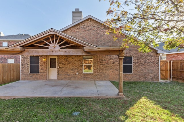 rear view of house featuring brick siding, a lawn, a patio, and fence