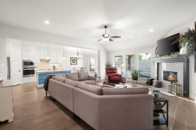 living room featuring dark wood-type flooring, lofted ceiling, a fireplace, and recessed lighting