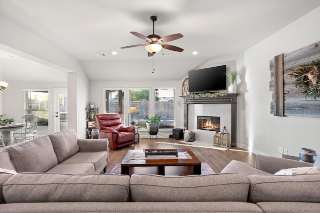 living room with recessed lighting, ceiling fan with notable chandelier, wood finished floors, vaulted ceiling, and a tiled fireplace