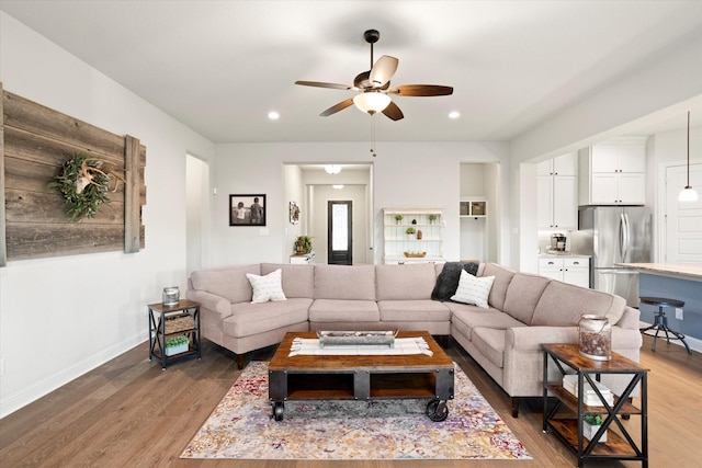 living room featuring a ceiling fan, baseboards, wood finished floors, and recessed lighting