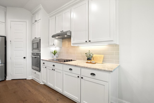 kitchen featuring light stone counters, under cabinet range hood, white cabinetry, appliances with stainless steel finishes, and backsplash