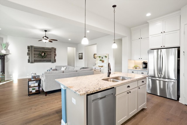 kitchen featuring appliances with stainless steel finishes, open floor plan, white cabinets, and an island with sink