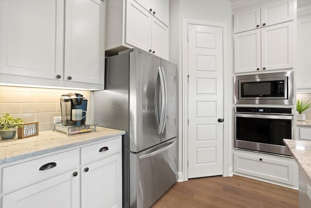 kitchen with light stone counters, dark wood-style flooring, stainless steel appliances, tasteful backsplash, and white cabinetry