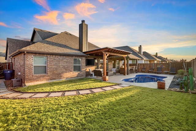 back of house at dusk with a fenced in pool, brick siding, a yard, a patio area, and a fenced backyard