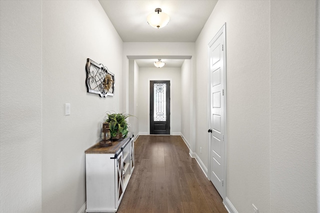 doorway featuring baseboards and dark wood finished floors