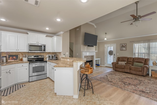 kitchen featuring stainless steel appliances, a breakfast bar, a peninsula, white cabinets, and open floor plan