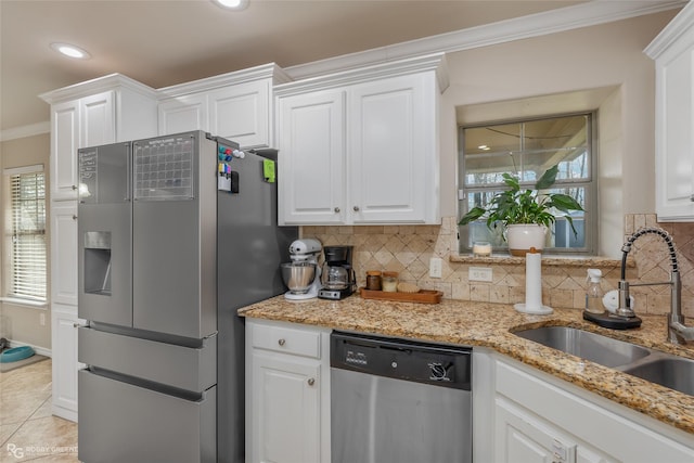 kitchen featuring stainless steel appliances, backsplash, ornamental molding, white cabinets, and a sink