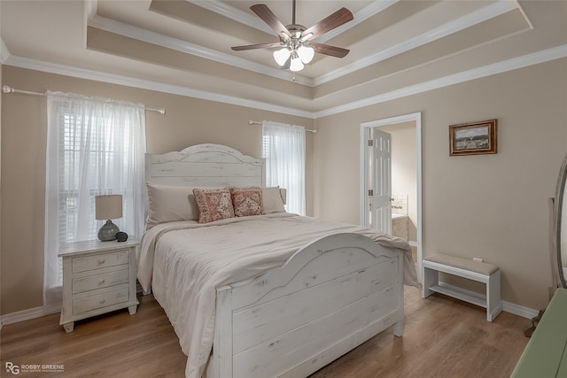 bedroom featuring light wood finished floors, ornamental molding, and a raised ceiling