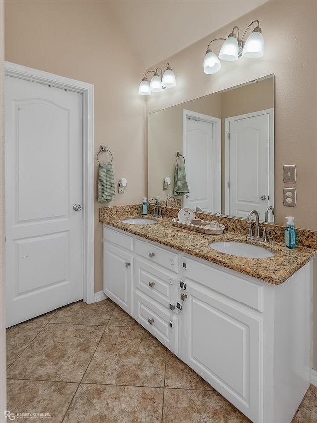 bathroom with tile patterned floors, a sink, lofted ceiling, and double vanity