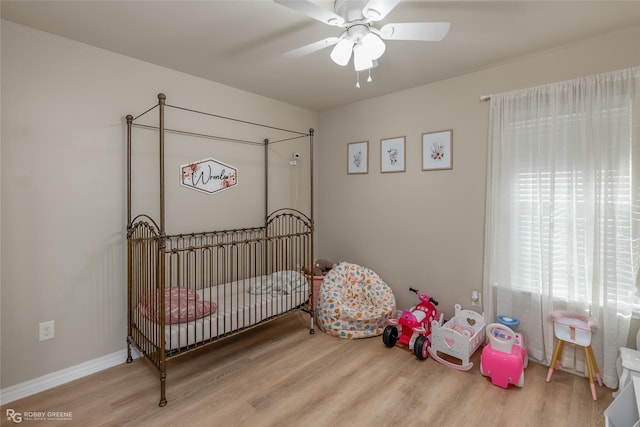 bedroom with light wood-type flooring, ceiling fan, and baseboards