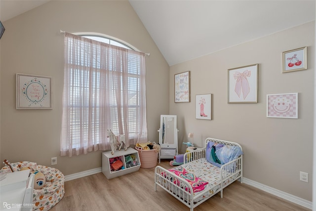 bedroom featuring lofted ceiling, light wood finished floors, and multiple windows