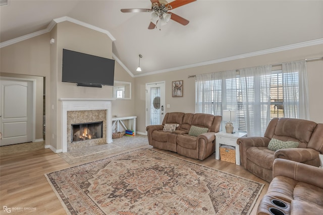 living area with ornamental molding, light wood-type flooring, high vaulted ceiling, and a tiled fireplace