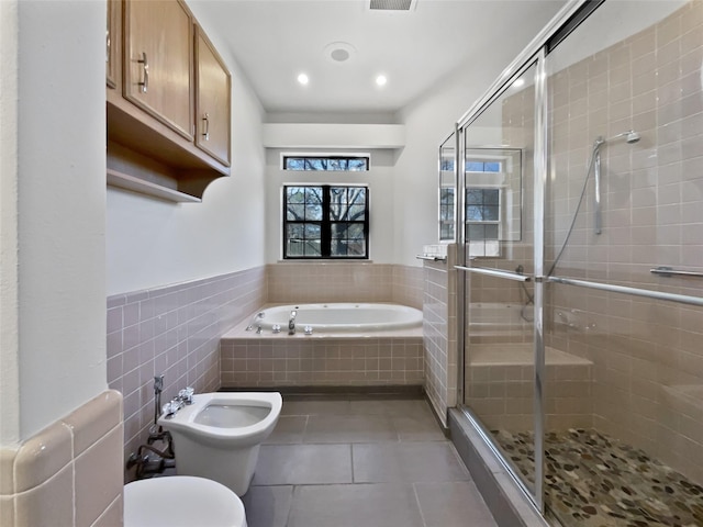 bathroom featuring toilet, tile patterned floors, a shower stall, a bidet, and tile walls