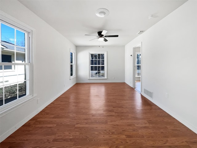 spare room featuring dark wood-style floors, visible vents, and baseboards