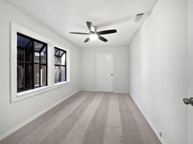 carpeted empty room featuring baseboards, visible vents, and a ceiling fan