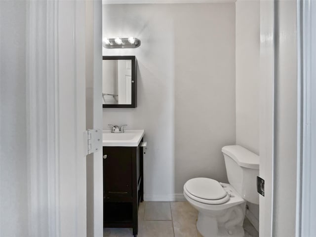 half bath featuring baseboards, vanity, toilet, and tile patterned floors