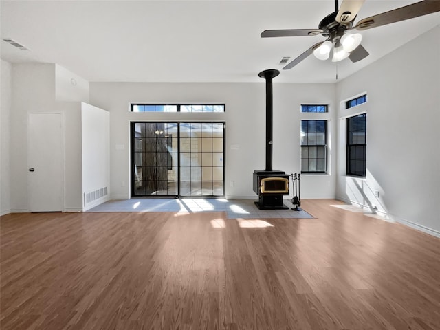 unfurnished living room with a wood stove, light wood-style flooring, and visible vents