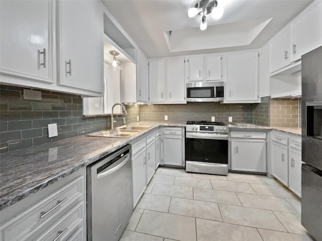 kitchen featuring white cabinetry, stainless steel appliances, a sink, and a raised ceiling